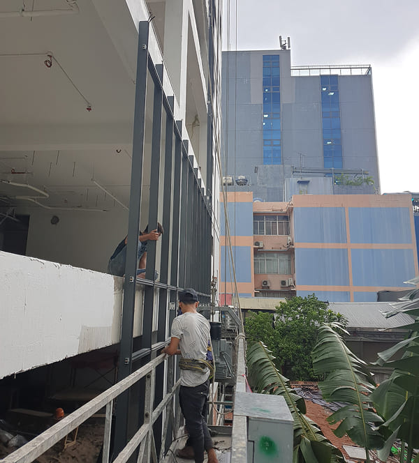 Thợ thi công của Minh Gia Door lắp đặt cửa kính cho tòa nhà văn phòng tại Quận 3